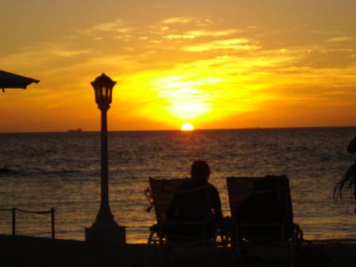 a person sitting in chairs watching the sunset on the beach at Location PanoramaGreen in Burg-Reuland
