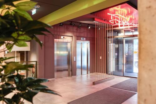 a lobby with glass doors and a neon sign on the wall at arte Hotel Wien Stadthalle in Vienna