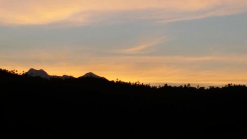 a sunset over a hill with mountains in the background at Imaj Private Villas in Senggigi 