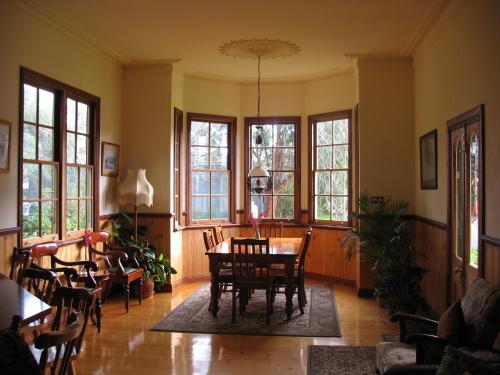 a dining room with a table and chairs and windows at Butterfly Farm Bed and Breakfast Nirranda in Nirranda