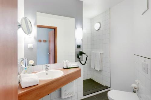 Hotel Wolfsburg Centrum, Affiliated by Meliá في فولفسبورغ: حمام أبيض مع حوض ومرحاض