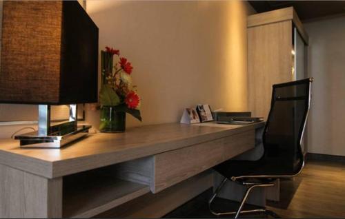a desk with a vase of flowers on top of it at bai Hotel Cebu in Cebu City