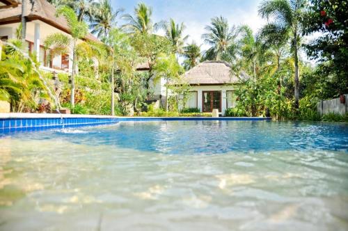 a swimming pool in front of a house at Imaj Private Villas in Senggigi 
