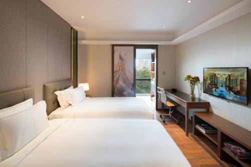 a hotel room with two beds and a desk at Fraser Suites Shenzhen, Near Huaqiang North Business Zone and next to shopping mall complex, with direct subway access in Shenzhen