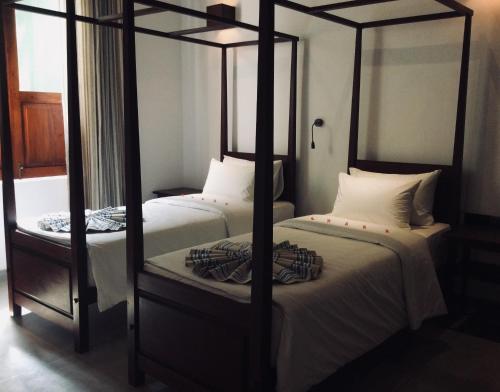 two twin beds in a room with two posts at Coza Ceylon in Mount Lavinia