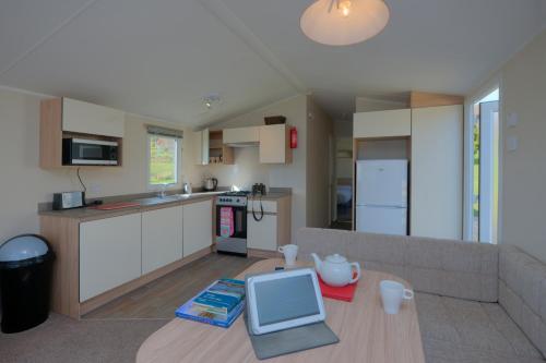 a living room with a couch and a kitchen at Appin Holiday Homes -Caravans, Lodges, Shepherds Hut and Train Carriage stays in Appin