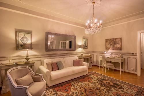 Domus Verona - Incantevole residenza difronte a casa Giulietta في فيرونا: غرفة معيشة مع أريكة وكراسي ومرآة