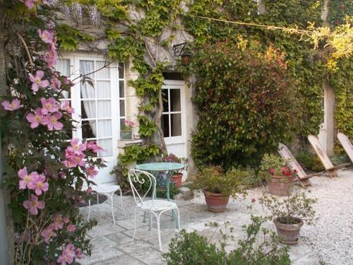 un tavolo e sedie di fronte a una casa con fiori di la glycine a Asnelles