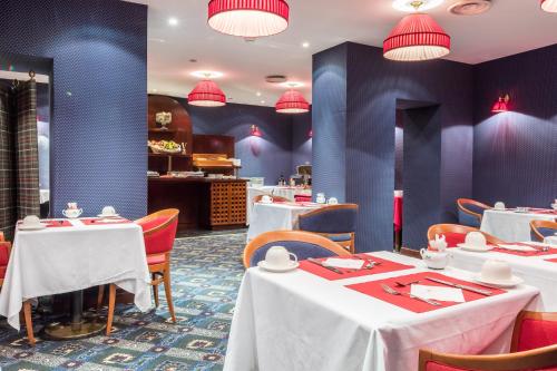 a restaurant with white tables and red chairs at Villa Panthéon in Paris