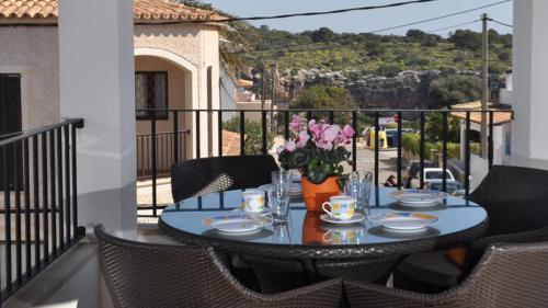 una mesa con un jarrón de flores en el balcón en Apartamentos Casa María, en Cala Figuera