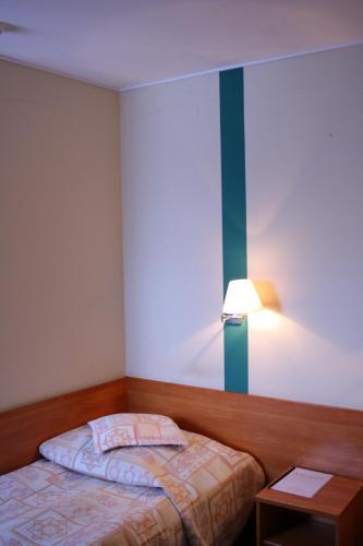 a small bedroom with a bed and a lamp at Amicus Żoliborz in Warsaw