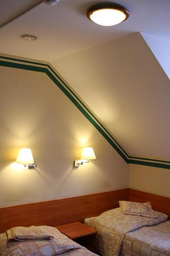 two beds in a room with green stripes on the wall at Amicus Żoliborz in Warsaw