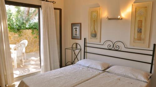 a bedroom with a large bed and a balcony at Apartamentos Casa María in Cala Figuera