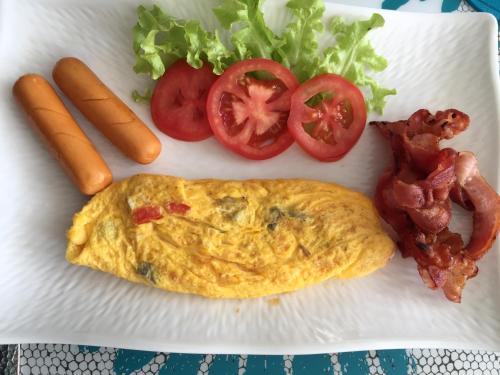 a white plate with an omelet and tomatoes and bacon at BC Summer Beach in Pran Buri