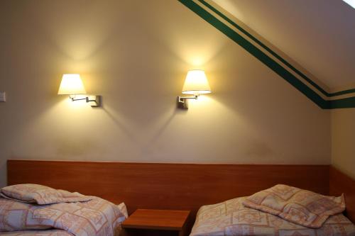 two beds in a room with two lights on the wall at Amicus Żoliborz in Warsaw