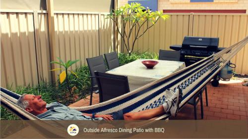a man laying in a hammock on a patio at SERENITY of MANDURAH STRA6210P5QC05G7 in Mandurah