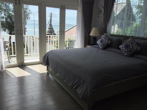 a bedroom with a bed and a balcony with a view at BC Summer Beach in Pran Buri