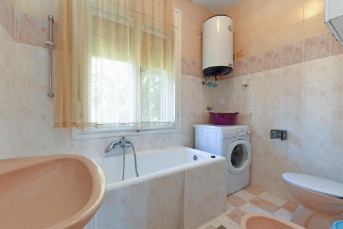 a bathroom with a tub and a washing machine at Apartments Josip 74 in Pula