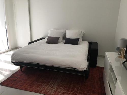 une chambre avec un lit avec des draps blancs et des oreillers dans l'établissement Carpe Diem, à Annecy