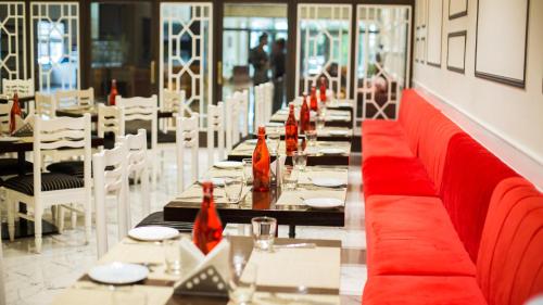 una larga fila de mesas en un restaurante con asientos rojos en Diamond Hotel, en Varanasi