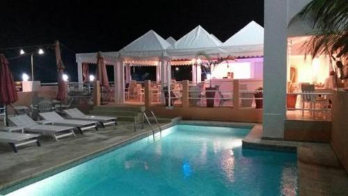 a swimming pool with chairs and a restaurant at night at Archotel in Dakar