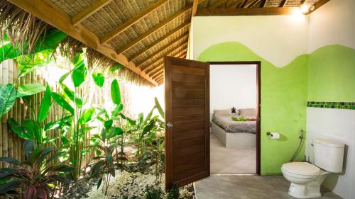 a bathroom with a toilet and a bed in a room at SandShine Village in Srithanu