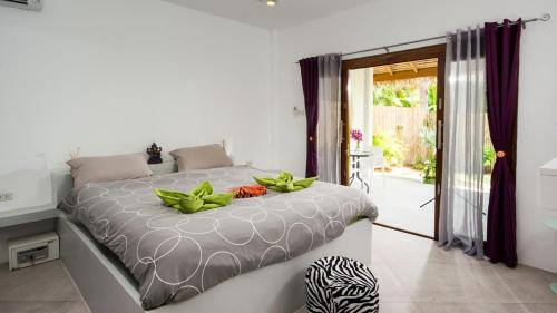 a bedroom with a bed with green plants on it at SandShine Village in Srithanu