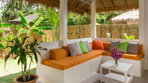 a porch with a couch with colorful pillows at SandShine Village in Srithanu