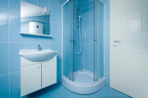 a blue bathroom with a shower and a sink at Panorama lux apartment in Rogoznica