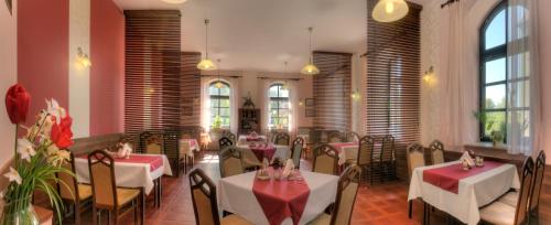 a dining room with tables and chairs and windows at Penzion U Hraběnky in Petrovice