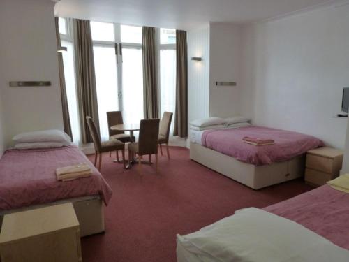 ロンドンにあるBelsize Park Apartmentsのベッド2台、テーブルと椅子が備わるホテルルームです。