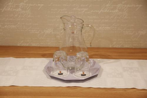 a glass vase with three glasses on a plate at WINE & ROSE BOUTIQUE HOTEL in Kharkiv