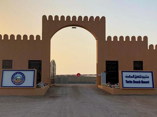 a gate to a building in the desert at Turtle Beach Resort in Al Ḩadd