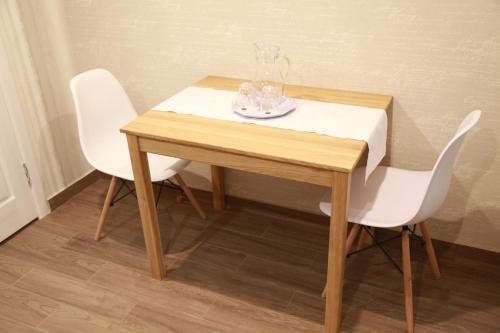a wooden table with two white chairs and a vase on it at WINE & ROSE BOUTIQUE HOTEL in Kharkiv