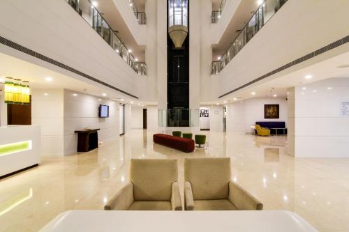 a lobby with a couch and chairs in a building at Lemon Tree Hotel, Banjara Hills, Hyderabad in Hyderabad