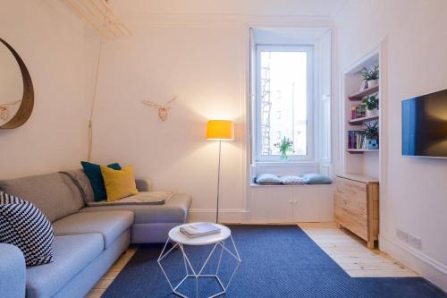 a living room with a couch and a window at Historic Edinburgh 1890s Home Turned Relaxing Retreat in Edinburgh