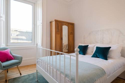 a bedroom with a bed and a chair and a window at Historic Edinburgh 1890s Home Turned Relaxing Retreat in Edinburgh