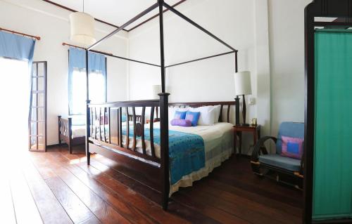 um quarto com uma cama de dossel e uma cadeira em The Apsara em Luang Prabang