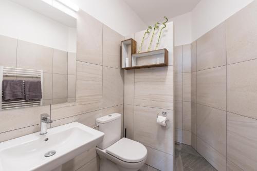 a white bathroom with a toilet and a sink at Barok Hotel and Apartments in Bratislava