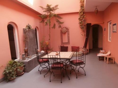 uma mesa e cadeiras num quarto com paredes cor-de-rosa em Maison Xanadu em Sidi Ifni