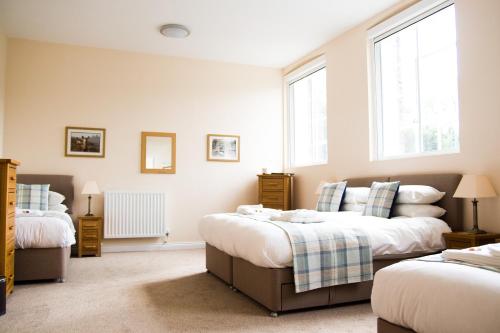 a bedroom with two beds and two windows at Gradbach Mill B&B in Buxton