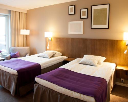 a hotel room with two beds and a chair at Best Western Plus Hotel Plaza in Västerås
