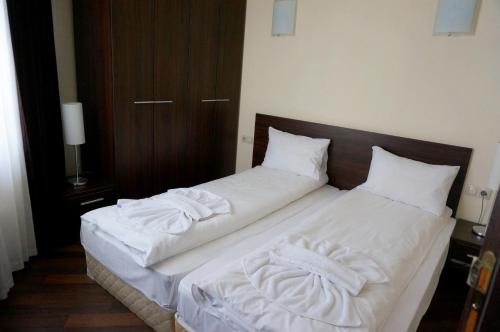 Una cama con sábanas blancas y almohadas. en GT Aspen House Apartments, en Bansko