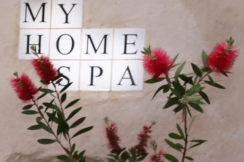 a sign that reads my homearma next to pink flowers at WUNDERGARTEN Dimora dei Frati in Gratteri