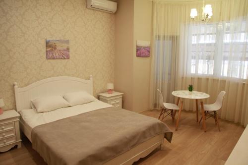 a bedroom with a bed and a table with chairs at WINE & ROSE BOUTIQUE HOTEL in Kharkiv