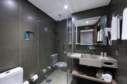 a bathroom with a shower and a sink and a mirror at Novotel Itajai in Itajaí