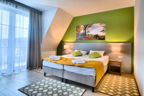 a bedroom with a bed with a green wall at Hotel Nowy Zdrój - Centrum Zdrowia i Wypoczynku in Polanica-Zdrój