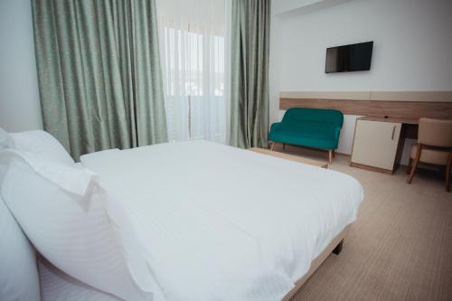 a bedroom with a white bed and a green chair at Tci Social Club in Cluj-Napoca