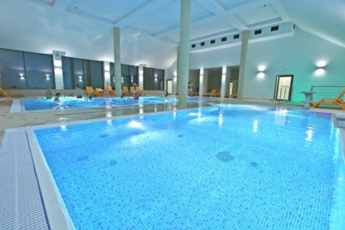 a large swimming pool with blue water in a building at Hotel Nowy Zdrój - Centrum Zdrowia i Wypoczynku in Polanica-Zdrój