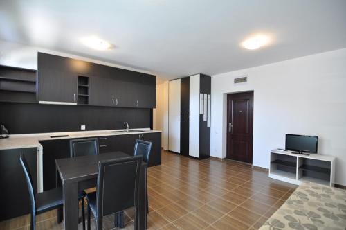 a kitchen with black cabinets and a table with chairs at Guest House ASK in Primorsko